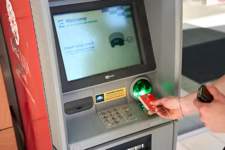 Mann hebt mit einer Bankkarte der Sparkasse an einem Geldautomaten in Montenegro Bargeld ab. Symbolbild Bankgebühren für Geldabhebungen im Ausland