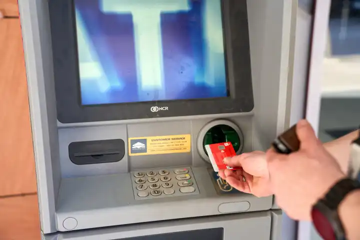 Kotor, Montenegro - May 5, 2024: Man withdraws cash from an ATM in Montenegro using a Sparkasse bank card. Symbolic image Bank charges for cash withdrawals abroad