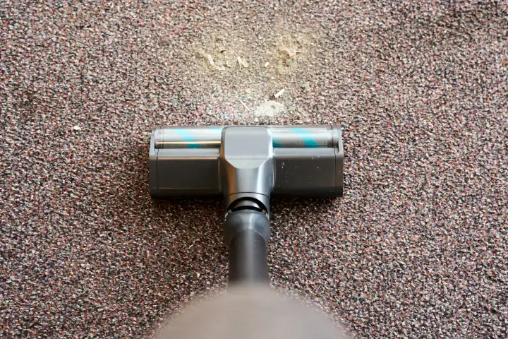 Staubsauger befreit einen Teppich im Haushalt von Staub und Dreck mit einer Bodendüse
