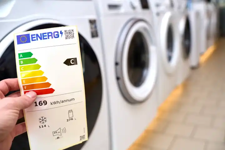 Augsburg, Bavaria, Germany - 18 May 2024: A hand holds a European Union energy label in a store selling household appliances such as washing machines