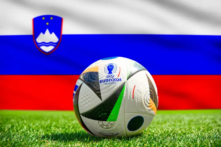 Fußball Europameisterschaft UEFA EURO 2024 in Deutschland: Offizieller Spielball von Adidas auf dem Spielfeld mit Nationalflagge von Slowenien. FOTOMONTAGE
