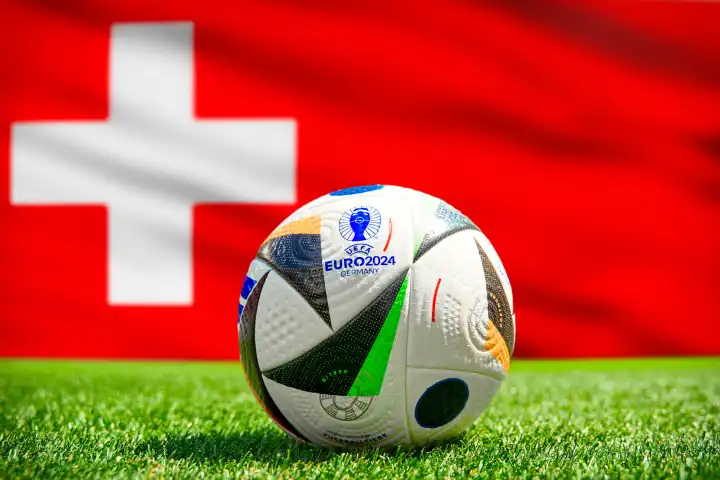 Fußball Europameisterschaft UEFA EURO 2024 in Deutschland: Offizieller Spielball von Adidas auf dem Spielfeld mit Nationalflagge von Schweiz. FOTOMONTAGE