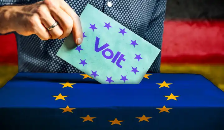 Themenbild Europawahl 2024 in Deutschland: Mann wirft einen Stimmzettel in eine Wahlurne mit Flagge der Europäischen Union. Stimmabgabe für die Partei: Volt. FOTOMONTAGE