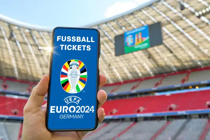 Hand hält Smartphone in Fußball Stadion mit dem UEFA EURO 2024 Logo und dem Schriftzug: Fussball Tickets. Symbolbild Eintrittskarten für die Europameisterschaft 2024. FOTOMONTAGE