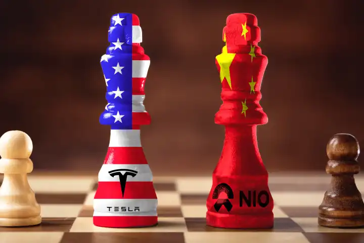 Schachfiguren stehen sich gegenüber, Figur mit USA Flagge und dem Tesla Logo und Figur mit China Flagge und NIO Logo. E-Auto Hersteller in Konkurrenz. FOTOMONTAGE