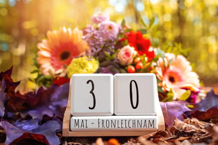 Blumengesteck mit einem Datumwürfel mit dem Datum 30 Mai, Fronleichnam Feiertag. FOTOMONTAGE