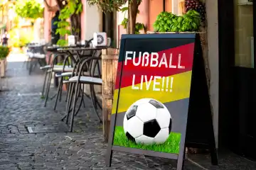 Fußball Live!! Schriftzug mit Deutschlandflagge auf einem Schild vor einem Gastronomiebetrieb. Symbolbild Public Viewing der Fußball Europameisterschaft 2024. FOTOMONTAGE 