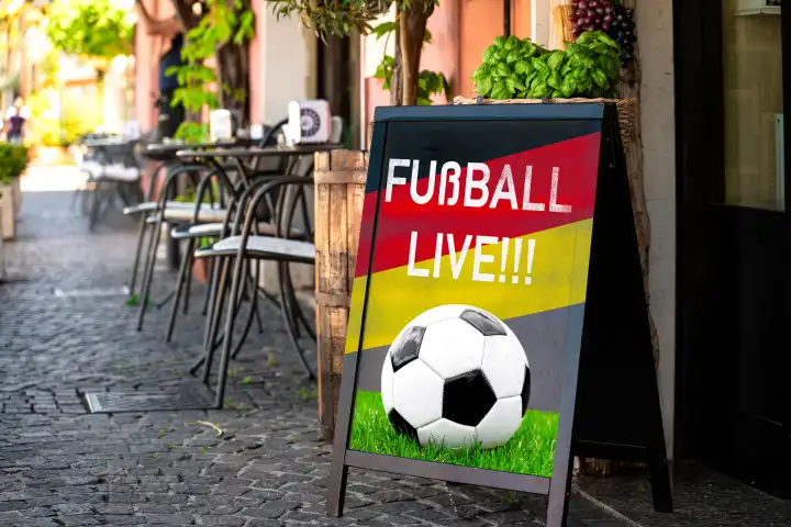 Fußball Live!! Schriftzug mit Deutschlandflagge auf einem Schild vor einem Gastronomiebetrieb. Symbolbild Public Viewing der Fußball Europameisterschaft 2024. FOTOMONTAGE 