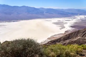 Blick auf das Death Valley in den USA, eine beeindruckende Wüstenlandschaft mit Bergketten und einem ausgedehnten Salzsee, bekannt für seine extreme Trockenheit und Hitze
