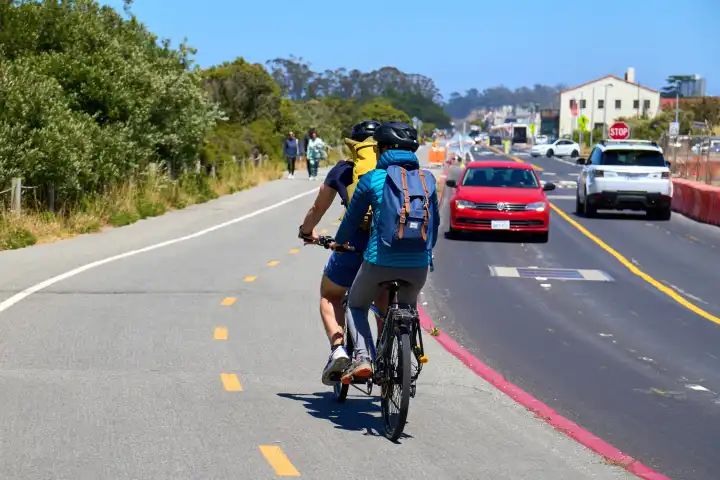  San Francisco, California, United States of America - June 14, 2024: Cyclist on a tandem on a bike path next to a street in San Francisco