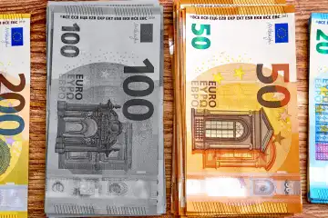 Mehrere Bündel von Eurobanknoten in verschiedenen Nennwerten (50, 100, 200 Euro). Es symbolisiert Schwarzgeld und illegale geheime Finanzpraktiken wie Geldwäsche, Steuerhinterziehung und Schattenwirtschaft. Die Banknoten repräsentieren unversteuertes Einkommen und finanzielle Vergehen. FOTOMONTAGE