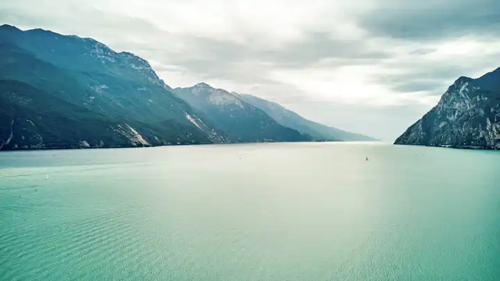 Riva del Garda, Lake Garda, Italy - June 24, 2024: Above the clouds of Lake Garda in summer, aerial view with a drone. Water of the lake in the beautiful mountain landscape of the tourist magnet.