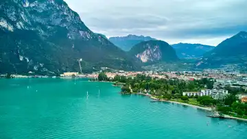 Riva del Garda, Lake Garda, Italy - June 24, 2024: impressive panoramic image of Lake Garda perfectly captures the majestic beauty of this Italian vacation region. Turquoise waters reflect the mountain walls and create a picturesque backdrop to the lake's surroundings.