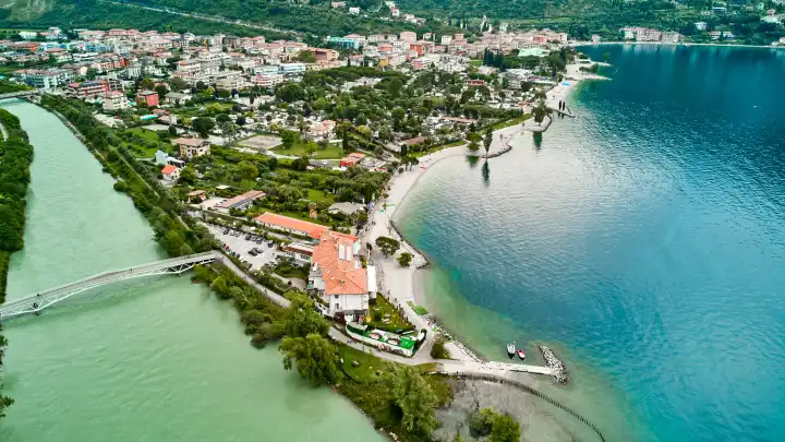 Nago Torbole, Garda, Italy - June 24, 2024: Water flows from the Sarca River into Lake Garda in the northern vacation resort of Torbole after persistent rainfall and storms.Lake has a high water levelLake has high water level. 
Aerial view of the Sarca River in the northern town of Torbole on Lake Garda