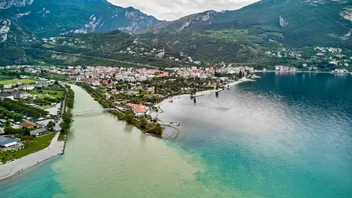 Nago Torbole, Garda, Italy - June 24, 2024: Water flows from the Sarca River into Lake Garda in the northern vacation resort of Torbole after persistent rainfall and storms.Lake has a high water levelLake has high water level. 
Aerial view of the Sarca River in the northern town of Torbole on Lake Garda