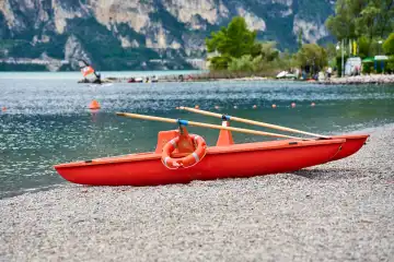 Torbole, Lake Garda, Italy - June 25, 2024: Lifeboat of the lifeguards at Lake Garda in Torbole is ready and waiting for a mission. Lifeguard sits in a chair and makes sure that nobody drowns or has an accident in the lake.