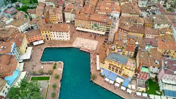 Riva del Garda, Lake Garda, Italy - June 25, 2024: A bird's eye view of Riva del Garada, the beautiful old town invites you to store and buy souvenirs of Lake Garda. You can also see Torre Apponale, the town tower, an absolute sight.