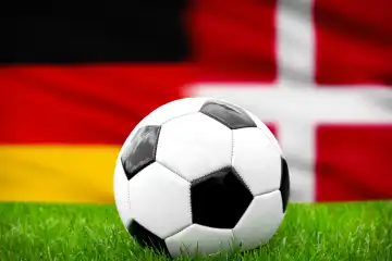 Fußball Europameisterschaft Länderspiel im Achtelfinale Deutschland Dänemark. Ein Fußball auf dem Spielfeld vor der deutschen und dänischen Flagge. FOTOMONTAGE