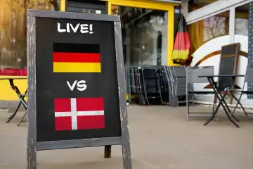 Fußball-Europameisterschaft 2024 Achtelfinale Symbolbild - Länderspiel Deutschland Dänemark. Public Viewing Konzept, eine Tafel vor einer Bar mit deutscher und dänischer Flagge und dem Schriftzug LIVE! FOTOMONTAGE