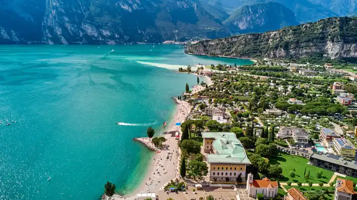 Nago Torbole, Lake Garda, Italy - June 26, 2024: Aerial view of the beach in Torbole on Lake Garda in Italy. The beach stretches along the clear, turquoise waters of the lake full of tourists sunbathing