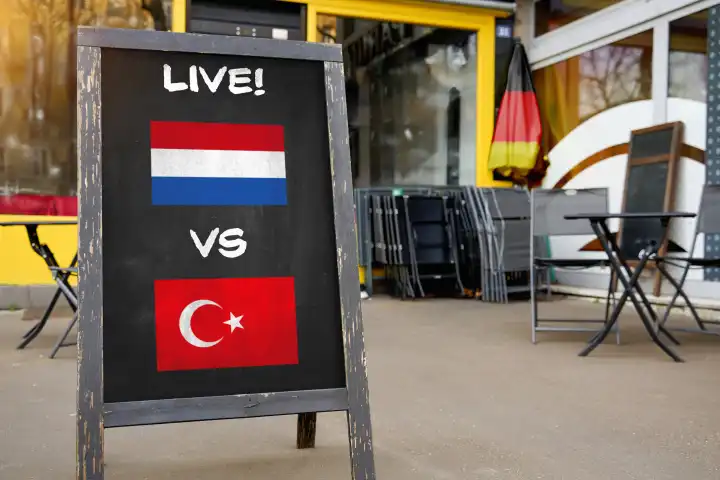 Fußball-Europameisterschaft 2024 Viertelfinale Symbolbild - Länderspiel Niederlande Türkei. Public Viewing Konzept, eine Tafel vor einer Bar mit niederländischer und türkischer Flagge und dem Schriftzug LIVE! FOTOMONTAGE