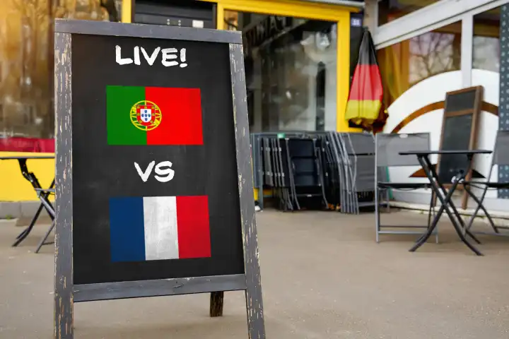 2 July 2024: European Football Championship 2024 quarter-finals symbol image - international match Portugal France. Public viewing concept, a board in front of a bar with Portuguese and French flags and the words LIVE! PHOTOMONTAGE