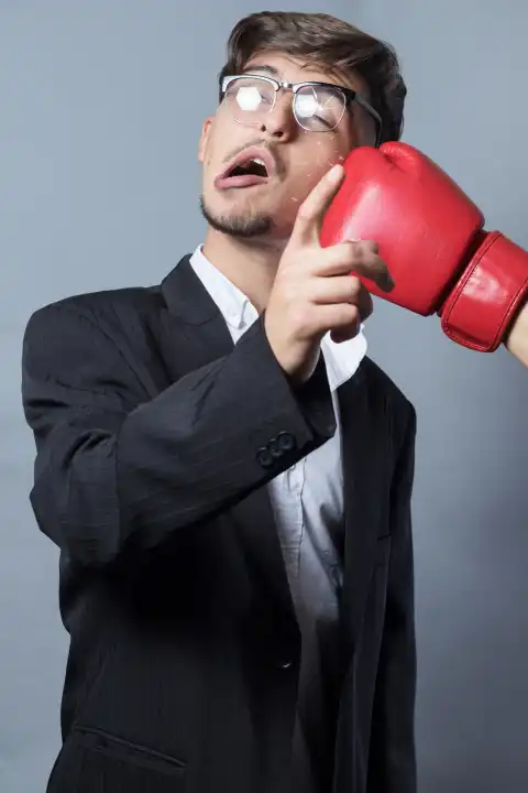 authoritarian Businessman with Glasses Hit by Fist of Box Gloves