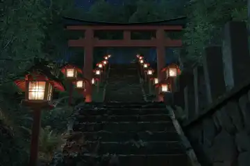 Alter japanischer Schrein mit rotem Torii-Tor und beleuchteten Holzlaternen