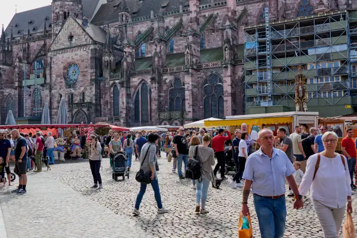 Freiburg, Deutschland - April 06, 2024: Menschen beim Einkaufen auf dem Marktplatz vor dem Freiburger Münster