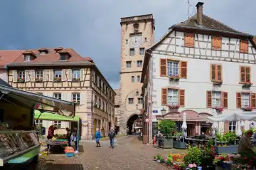Ribeauville, Elsass, Frankreich - 15. Juni 2024: Menschen auf dem Marktplatz vor dem Metzgerturm, einem mittelalterlichen Torturm in Ribeauvillé, Elsass, und einem Wahrzeichen des Dorfes