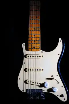 Detail of electric guitar on a black background between light or shadows