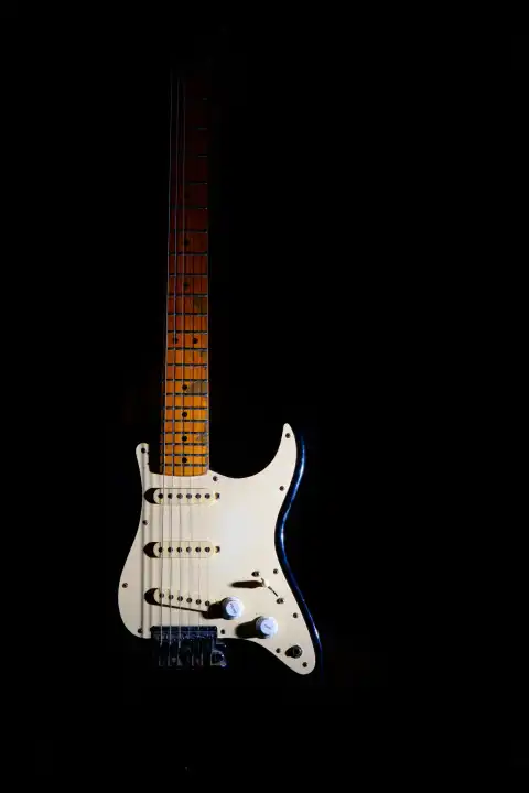 Electric guitar on a black background between light or shadows