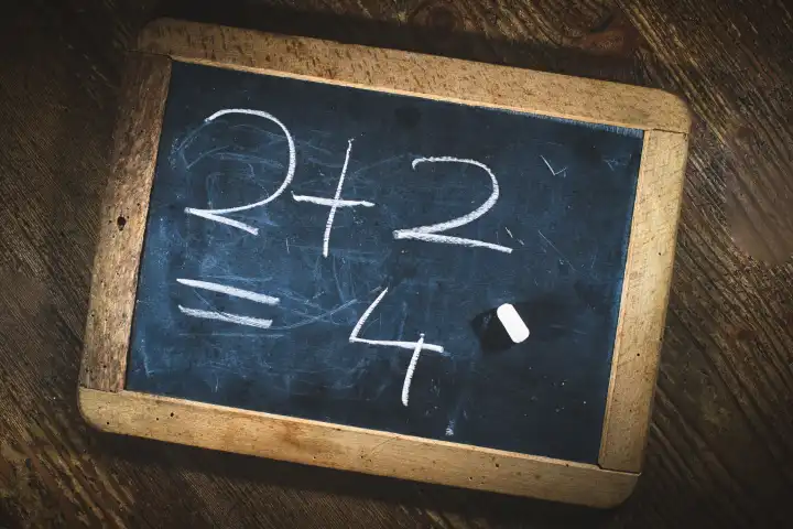 Simple child math calculation with chalk on small blackboard