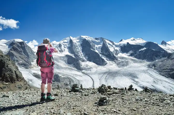 A woman observes and photographs high mountains during a hike