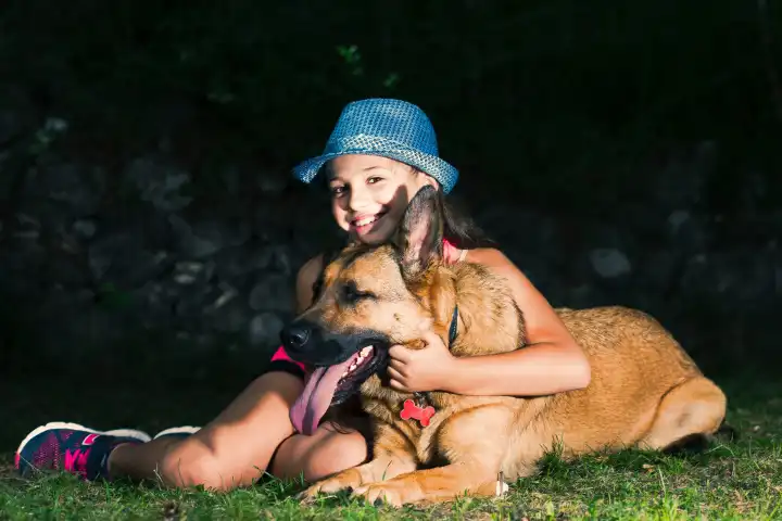 A little girl hugs her German shepherd dog.