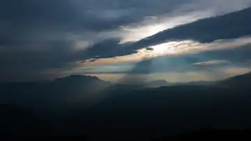 Berglandschaft mit Sonnenstrahlen, die durch die Wolken brechen,
