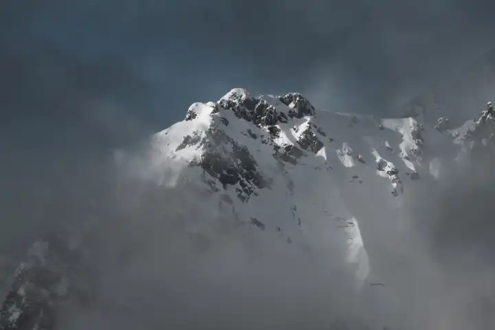 Verschneiter Berg in den Wolken in den italienischen Alpen