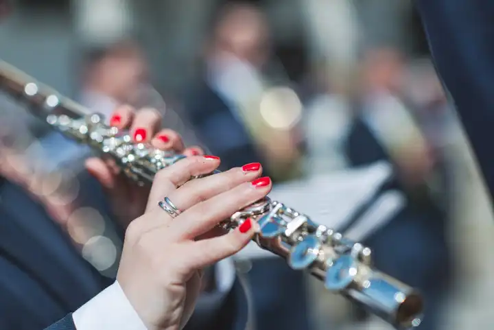 Detail of woman's hands playing transverse flute in a fanfare