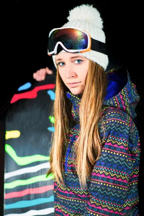 Girl with snowboard photographed in the studio with black background.