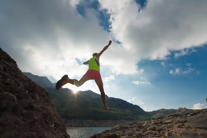 Girl training run while jumping near an alpine lake in the mountains at sunset