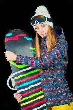 Sportliches Mädchen mit blauen Augen mit Snowboard auf schwarzem Hintergrund im Studio.