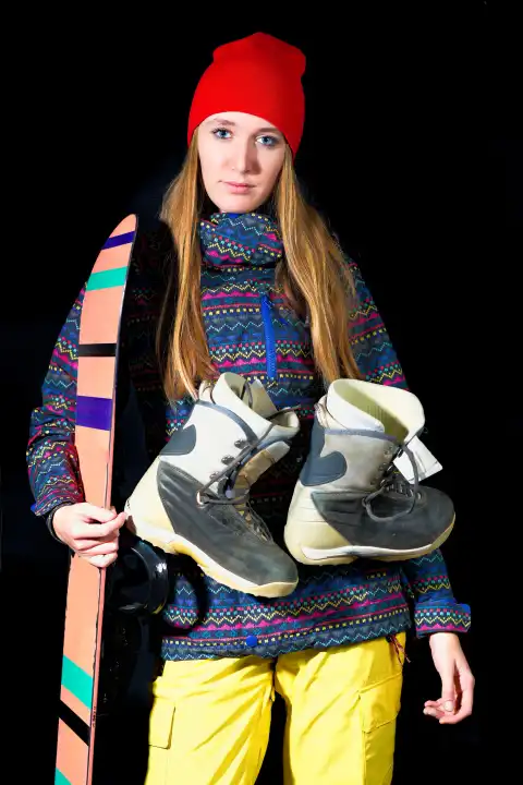 Sporty girl with snowboard equipment on black background in studio.