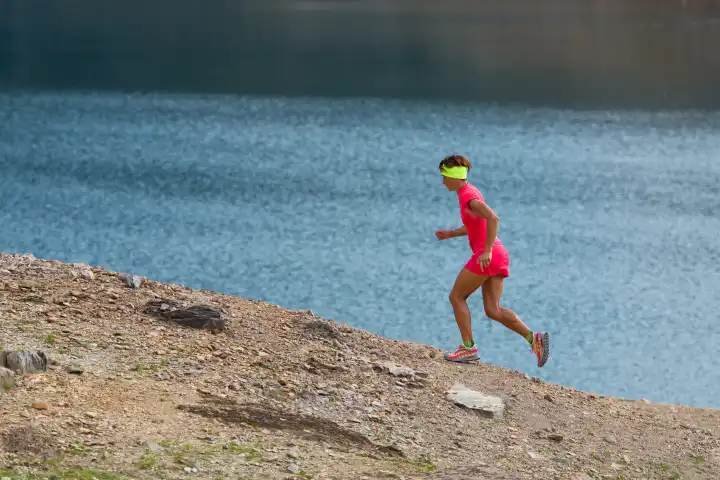 Woman running uphill workout for mountain running near an alpine lake
