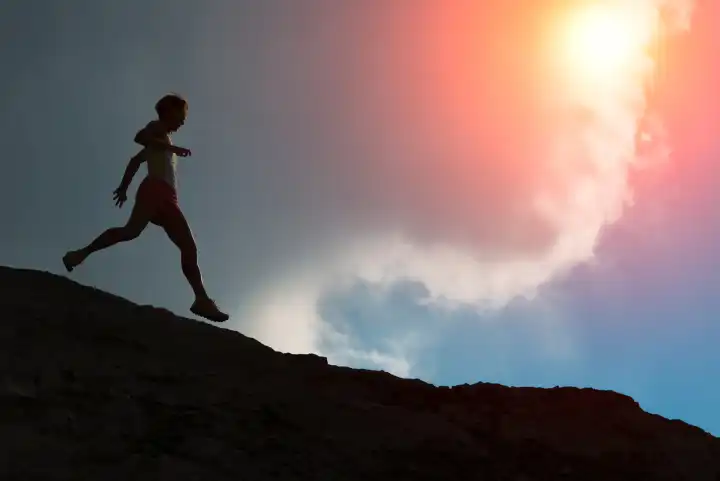 Downhill race on a mountain ridge with sun in the clouds in silhouette