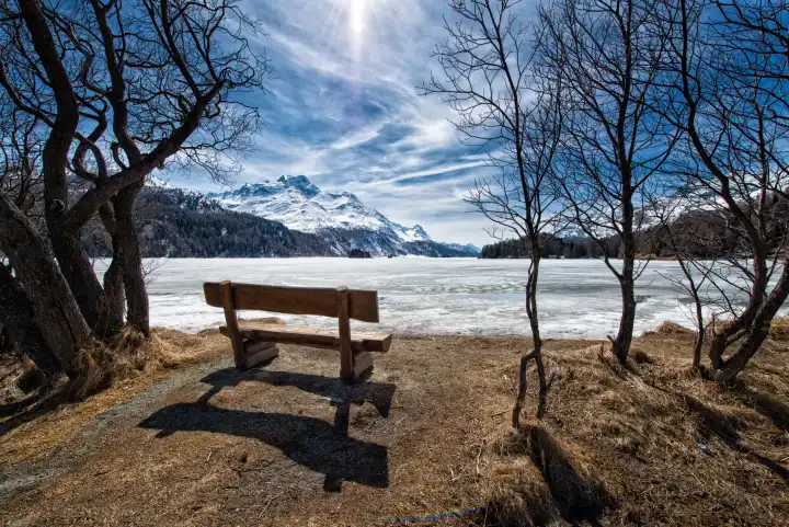 Holzbank zum Bewundern der Landschaft auf dem Eis eines Alpensees bei Sankt Moritz in der Schweiz