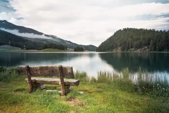 Wooden bench for tourists next to an alpine lake in the Swiss Alps