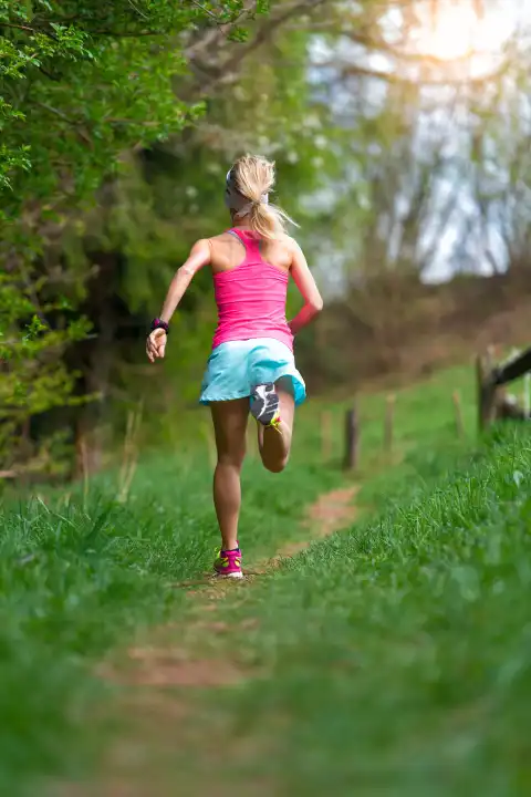 Blonde girl athlete running in a trail into the woods
