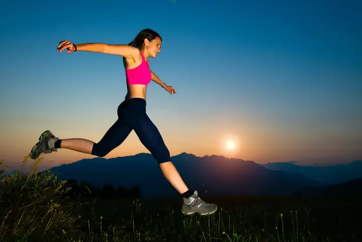 Mädchen springt bei Sonnenuntergang in den Bergen