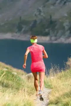 Girl with pink suit runs in the mountains to a lake
