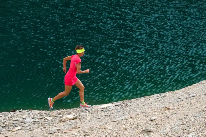 Girl with athletic body with full pink runs near a lake